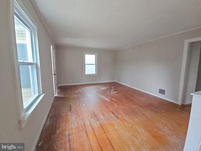 a view of empty room with window and wooden floor