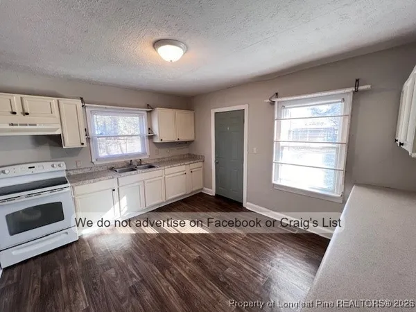 a kitchen with a refrigerator wooden floor and a stove top oven