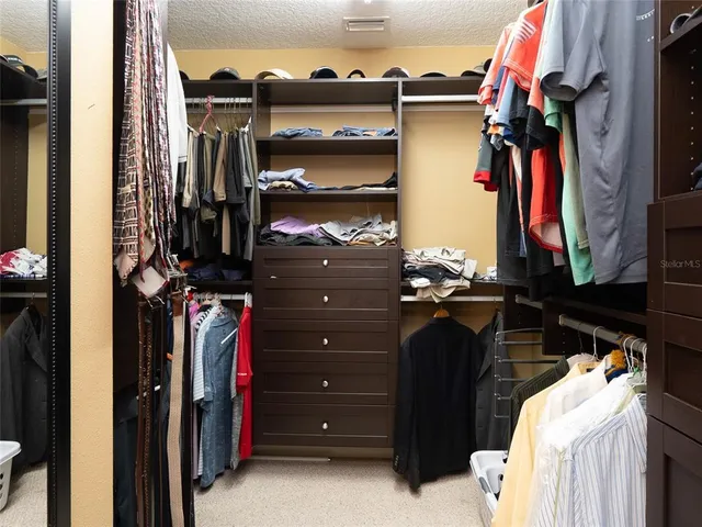 a view of walk in closet with clothes and shoes