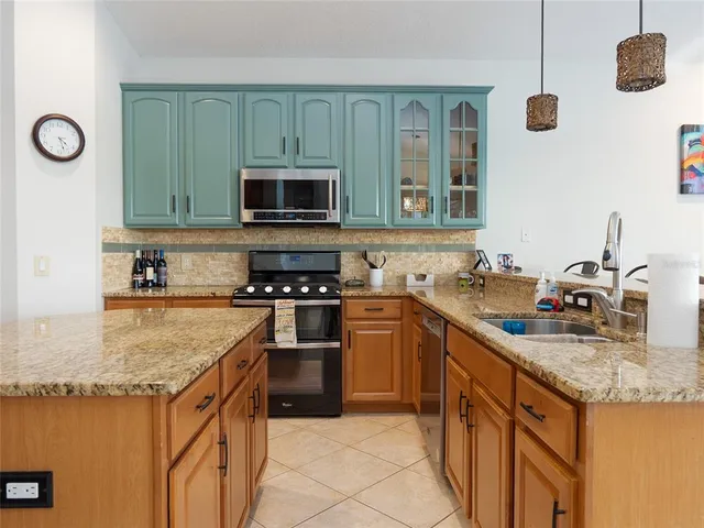 a kitchen with granite countertop kitchen island stainless steel appliances a stove sink microwave and refrigerator