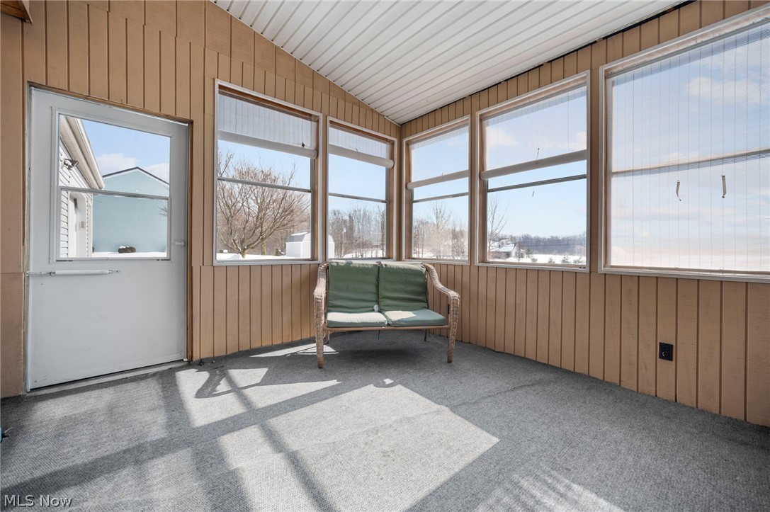 2099 Pontius Road Mogadore, OH 44260 - Photo 26 of 35 Sunroom featuring wooden walls, vaulted ceiling, and carpet