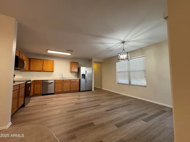 a large kitchen with stainless steel appliances granite countertop a stove a sink dishwasher and a refrigerator with wooden floor