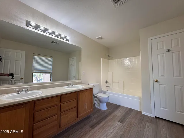 a spacious bathroom with a double vanity sink a toilet and a mirror