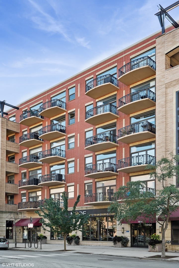 a front view of a building with lot of cars and trees