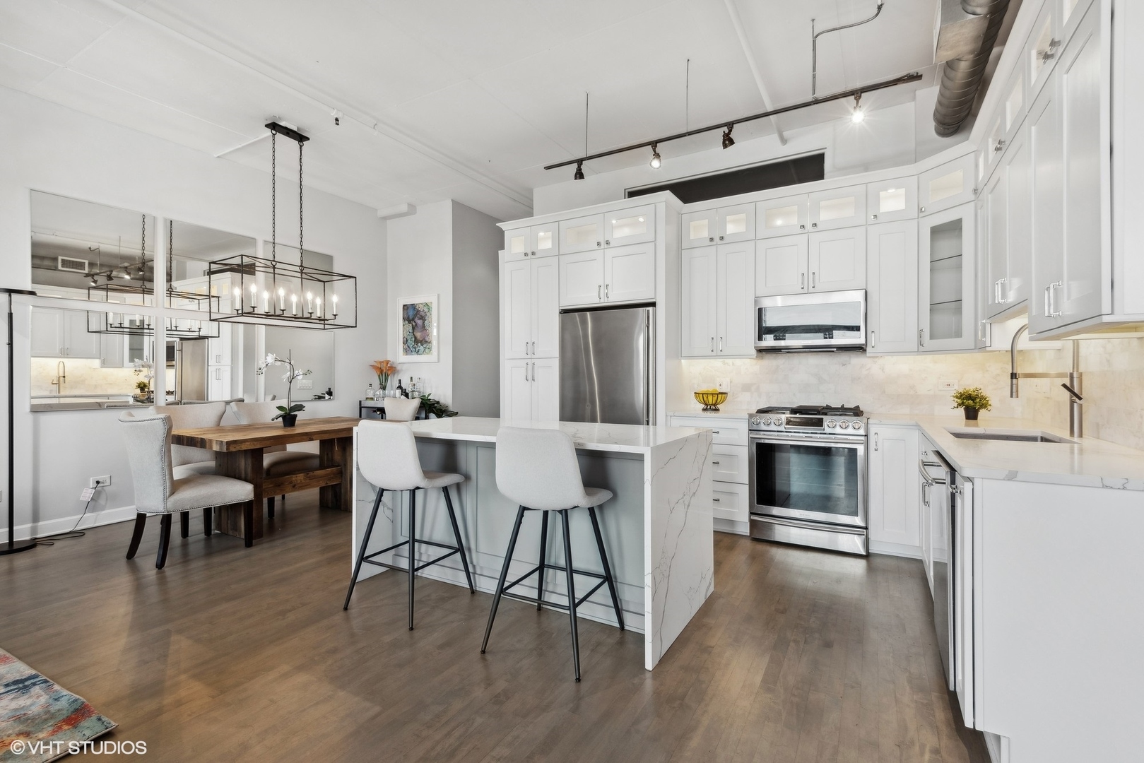 1301 West Madison Street, Unit 501 Chicago, IL 60607 - Photo 9 of 30 a kitchen with stainless steel appliances kitchen island granite countertop a table chairs stove and white cabinets