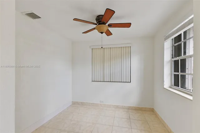 a view of empty room with window and ceiling fan