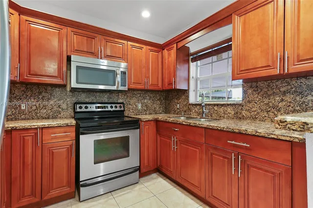 a kitchen with granite countertop wooden cabinets stainless steel appliances and a sink
