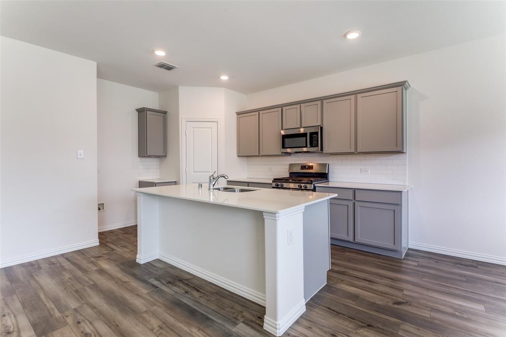 1207 Mesquite Lane Princeton, TX 75407 - Photo 6 of 25 a kitchen with stainless steel appliances a stove top oven a sink a refrigerator white cabinets and wooden floor
