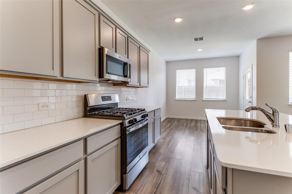 1207 Mesquite Lane Princeton, TX 75407 - Photo 8 of 25 a kitchen with granite countertop a sink wooden floor and stainless steel appliances