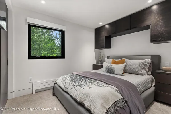 a bedroom with a large bed and a flat tv screen on dresser