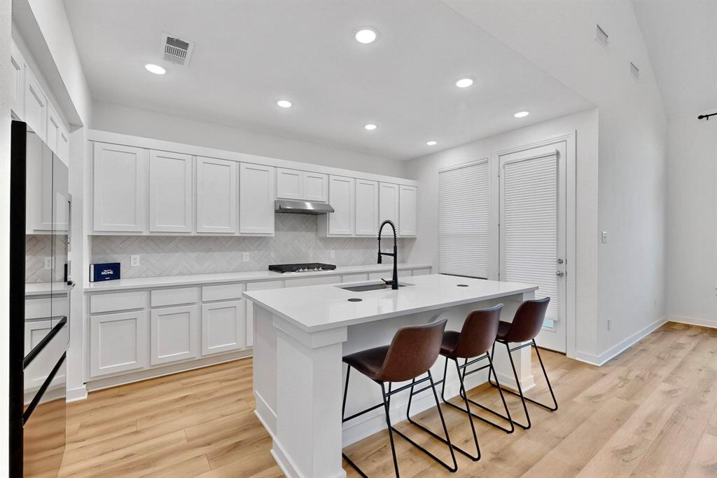 2017 Fall Crk Cove Mesquite, TX 75181 - Photo 8 of 40 Kitchen featuring decorative backsplash, a kitchen island with sink, white cabinets, a kitchen breakfast bar, and recessed lighting