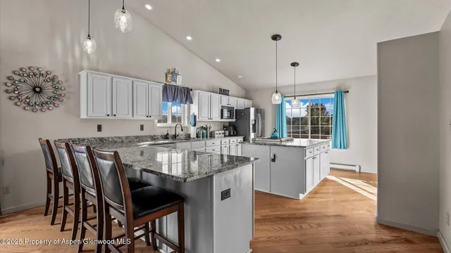 a kitchen with kitchen island granite countertop a table chairs sink and cabinets