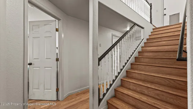 a view of staircase with wooden floor and white walls