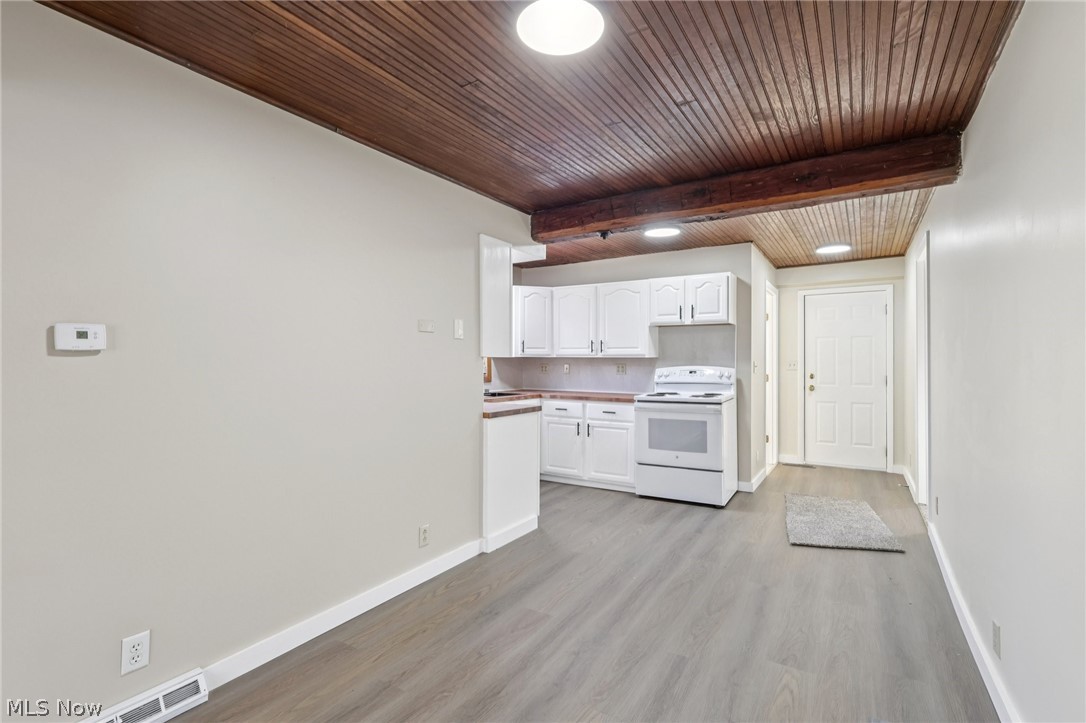 4200 Hattrick Road Rootstown, OH 44272 - Photo 10 of 42 Kitchen with white cabinetry, light wood-type flooring, white range with electric stovetop, and a wood ceiling with exposed beams