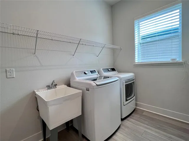 a large kitchen with stainless steel appliances a large counter top a stove and a refrigerator with wooden floor