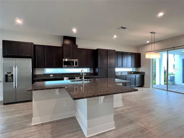 a large kitchen with stainless steel appliances granite countertop a sink a stove and a refrigerator