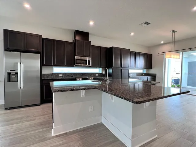 a kitchen with stainless steel appliances granite countertop a refrigerator and a stove top oven