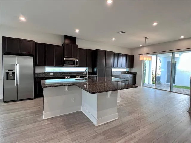 a kitchen with stainless steel appliances granite countertop a refrigerator a sink a stove a microwave and wooden cabinets