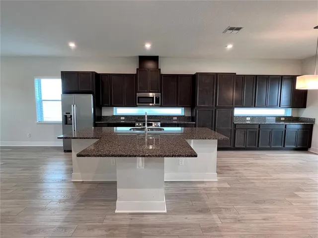 a kitchen with stainless steel appliances kitchen island granite countertop a stove a refrigerator and a sink