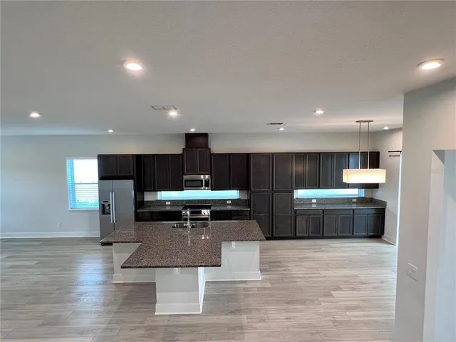 a kitchen with stainless steel appliances kitchen island granite countertop a stove a refrigerator and a sink