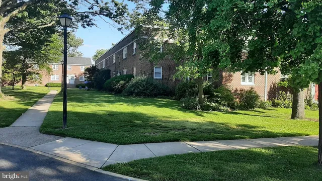a view of a fountain in front of a house with a big yard and large trees
