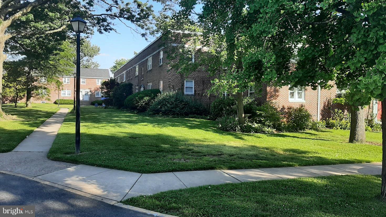 a view of a fountain in front of a house with a big yard and large trees