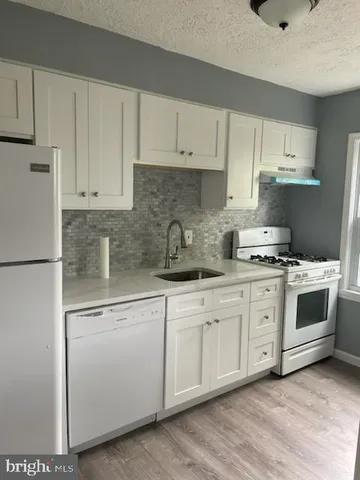 a kitchen with granite countertop white cabinets and white appliances