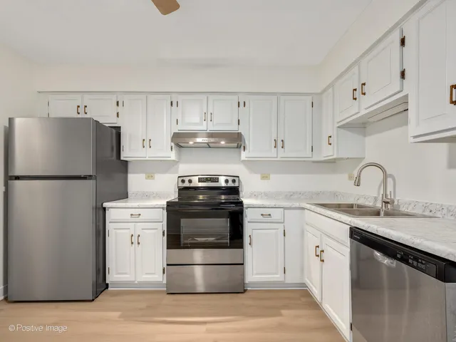 a kitchen with kitchen island a refrigerator and a sink