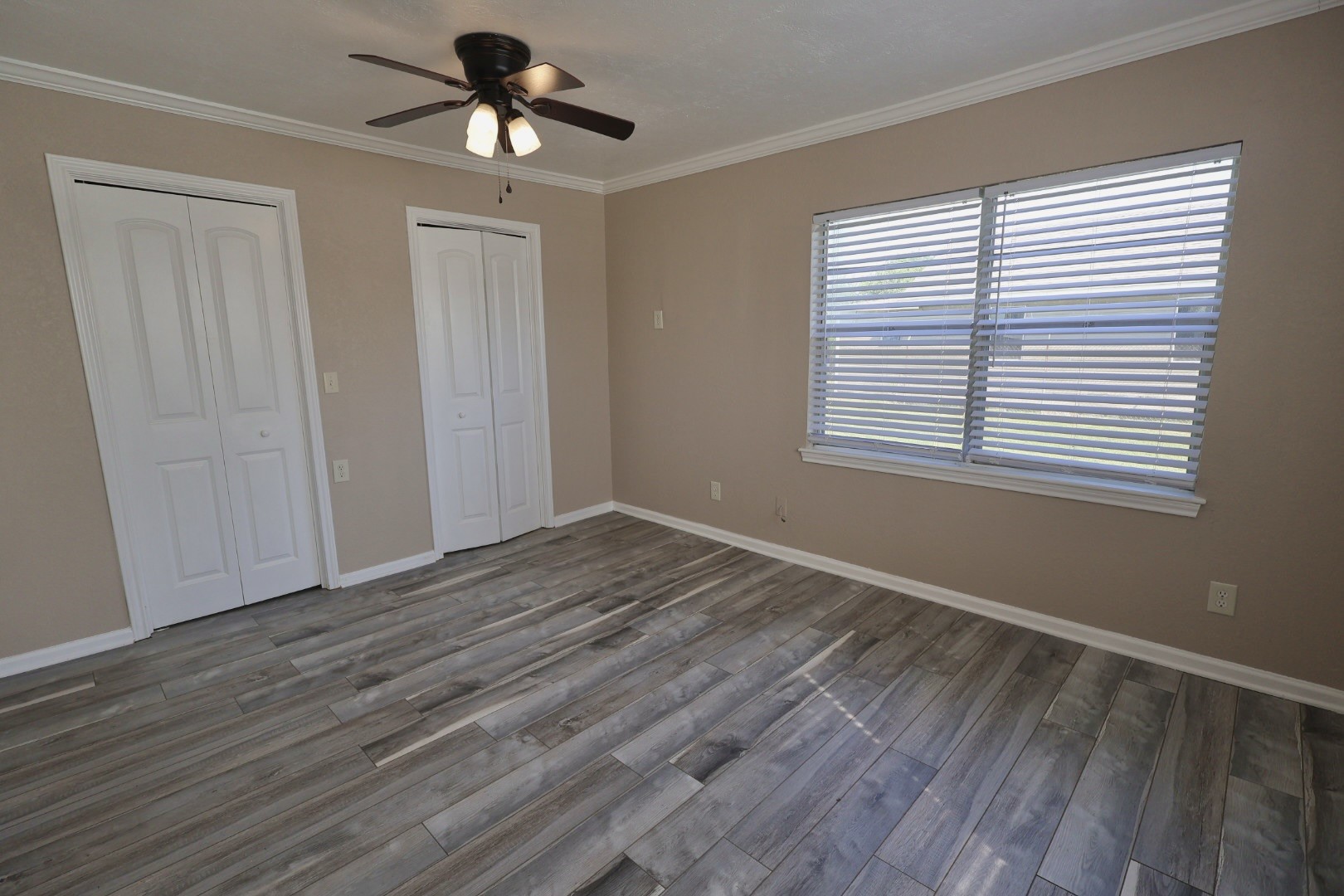 642 5th Street Dickinson, TX 77539 - Photo 10 of 20 Spacious primary bedroom featuring a ceiling fan, gleaming floors, and a generous walk-in closet, offering comfort and functionality.