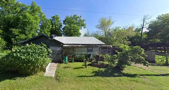 a backyard of a house with table and chairs plants and large trees