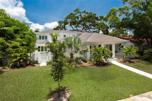 a view of a house with a big yard plants and large trees