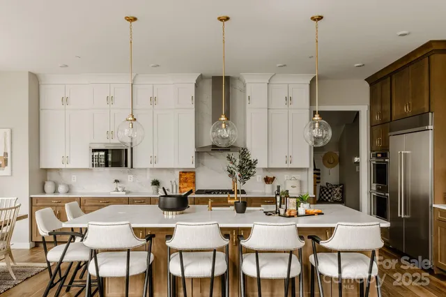 a view of kitchen with stainless steel appliances granite countertop dining table chairs and white cabinets