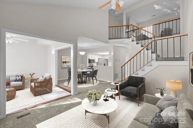 an empty room with kitchen view and a chandelier fan