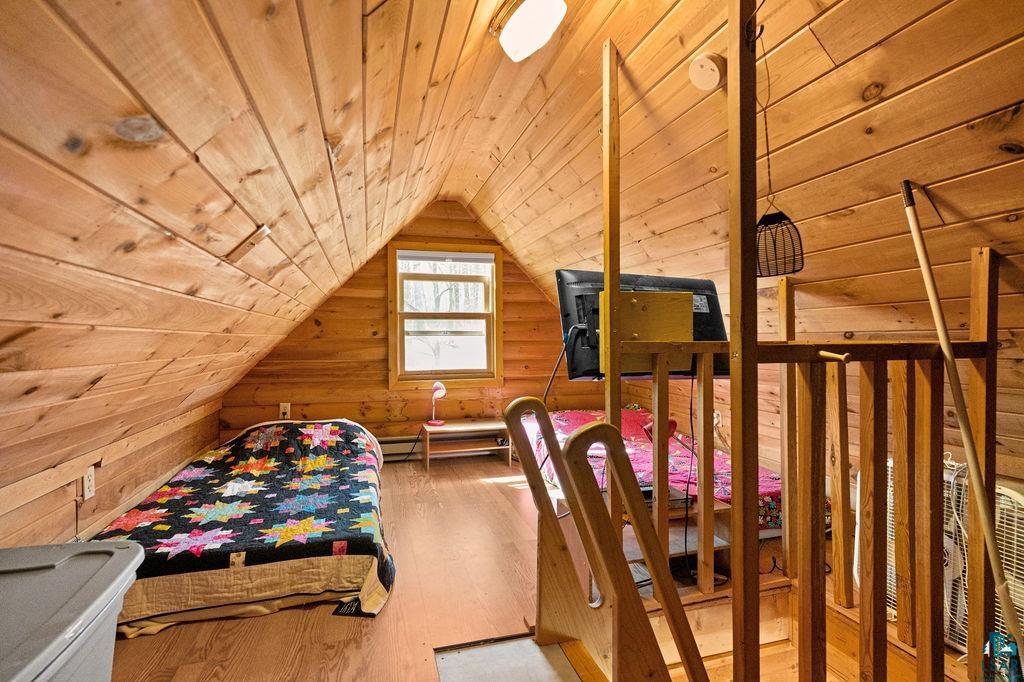 20663 Hardwood Loop Finlayson, MN 55735 - Photo 20 of 36 Attic space featuring wood-paneled walls and ceiling, a sloped ceiling, wood-finish flooring, and a single window with exterior views