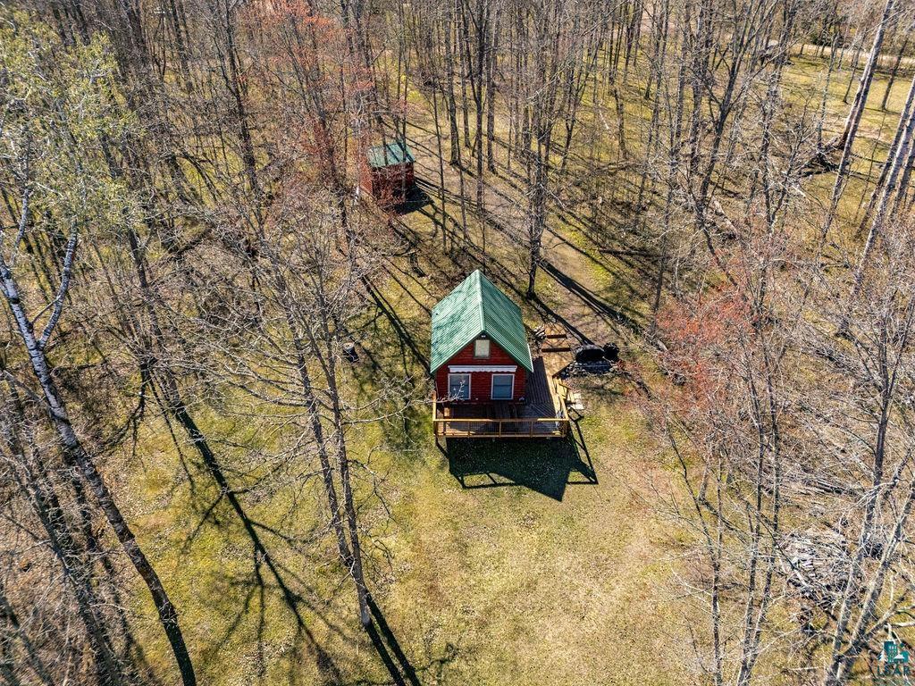 20663 Hardwood Loop Finlayson, MN 55735 - Photo 27 of 36 Red cabin with a green roof, elevated on a wooden deck, situated within a wooded clearing