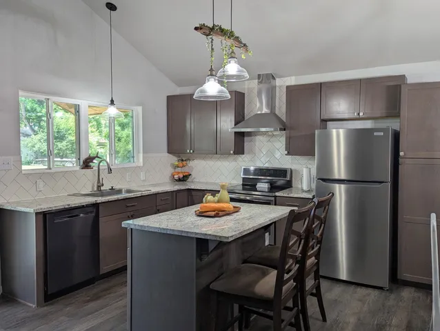 a kitchen with stainless steel appliances granite countertop a dining table chairs stove a refrigerator and cabinets