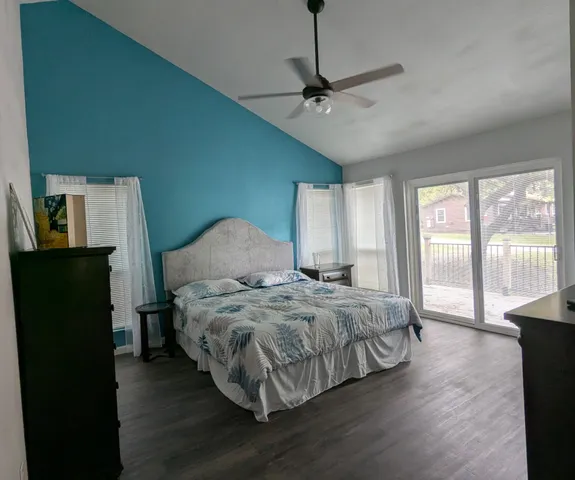 a bedroom with a bed a dresser and wooden floor