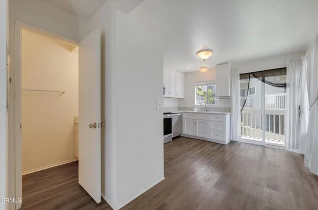 a kitchen with white cabinets and wooden floor