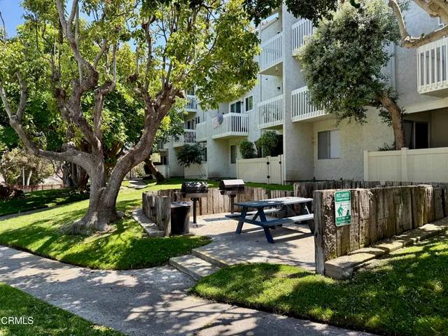 a view of a patio with couches table and chairs with wooden fence and plants