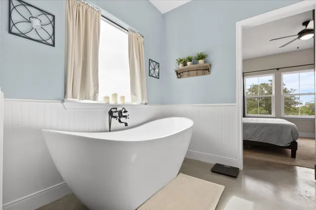 a white bath tub sitting in a bathroom next to a window
