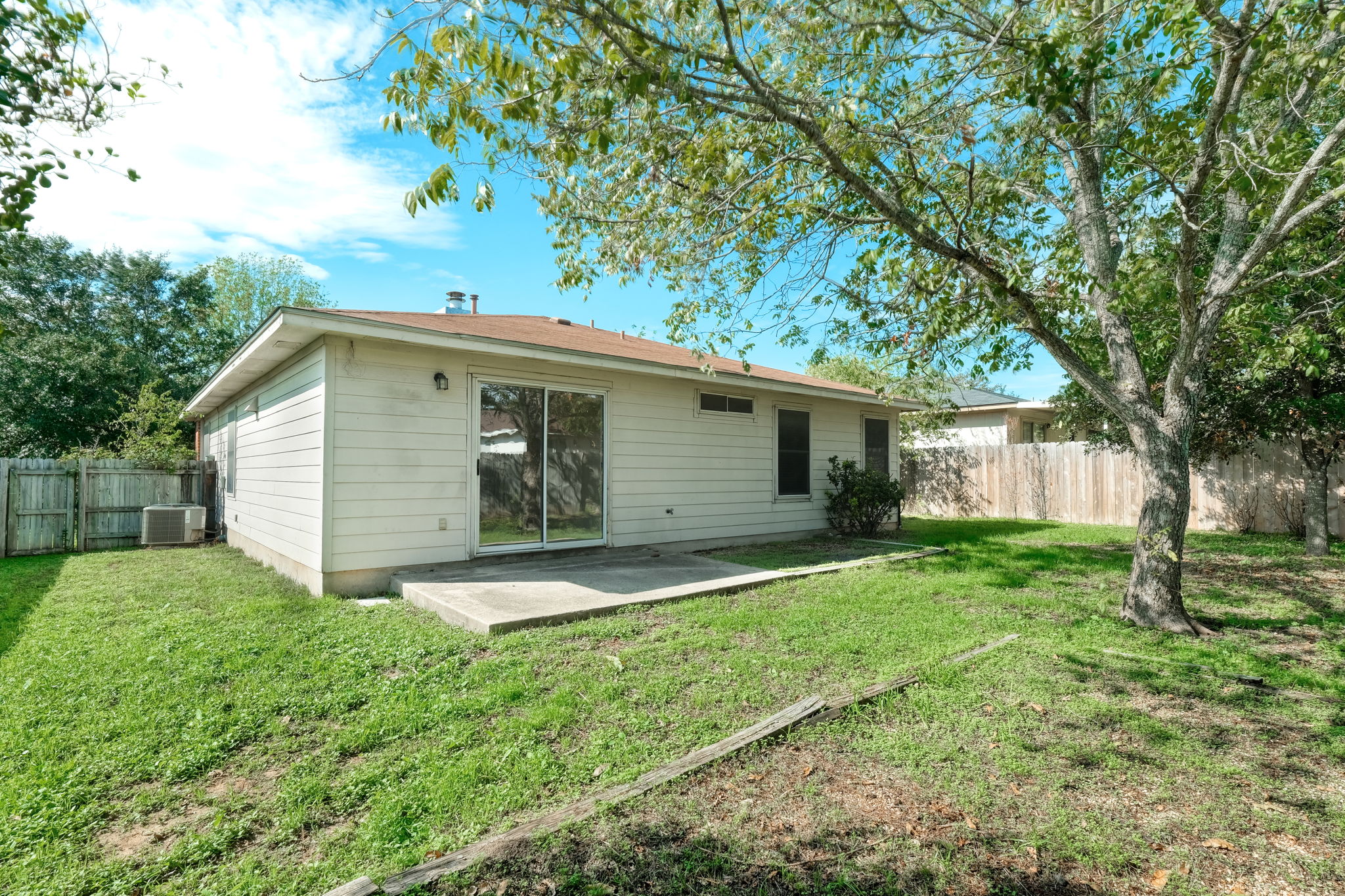 124 Hunter Rex Way Kyle, TX 78640 - Photo 12 of 14 Rear exterior featuring vinyl siding, a concrete patio, and a sliding glass door