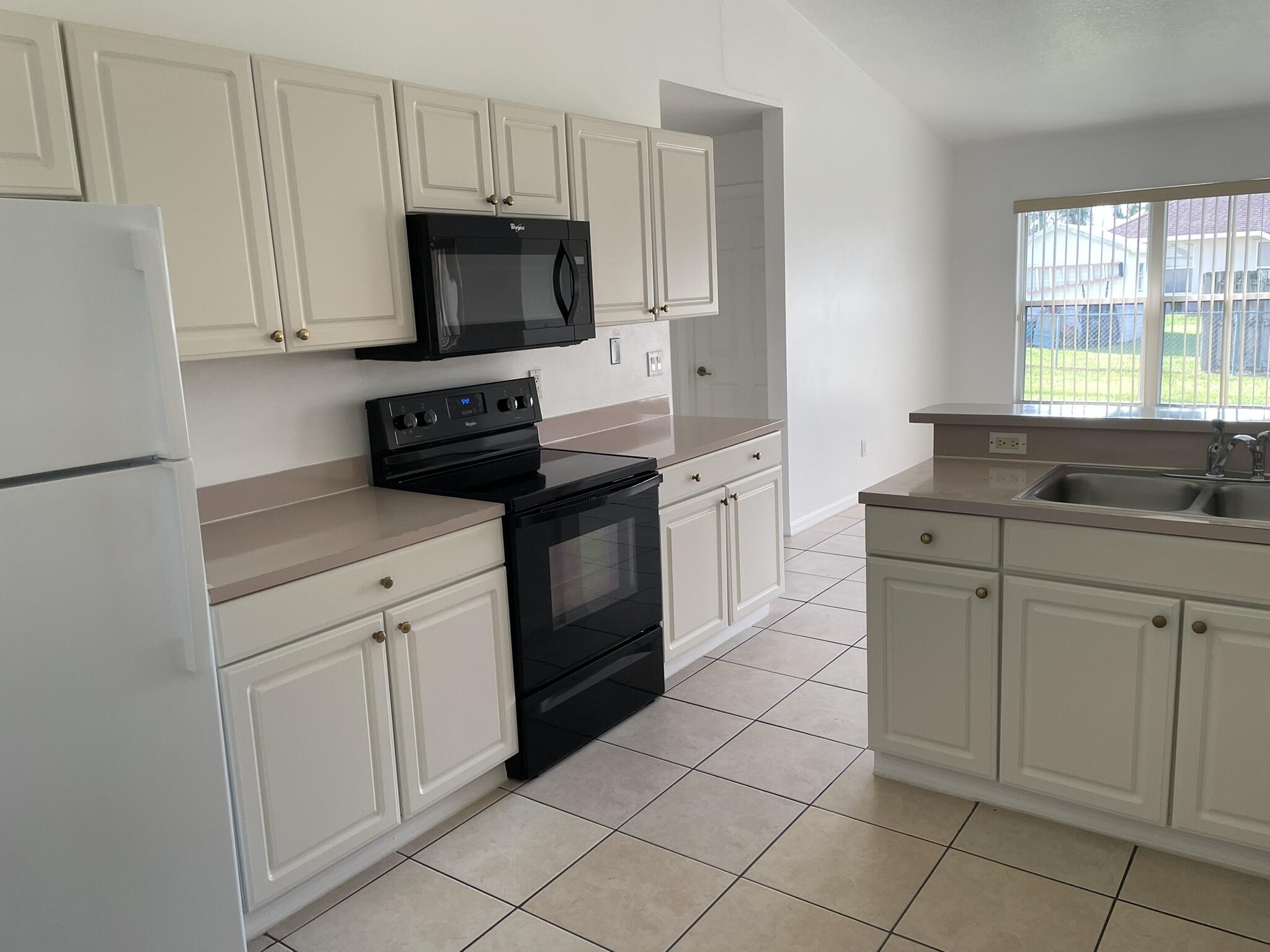4448 Northwest Bighorn Avenue Port St. Lucie, FL 34983 - Photo 6 of 19 a kitchen with cabinets appliances and a window