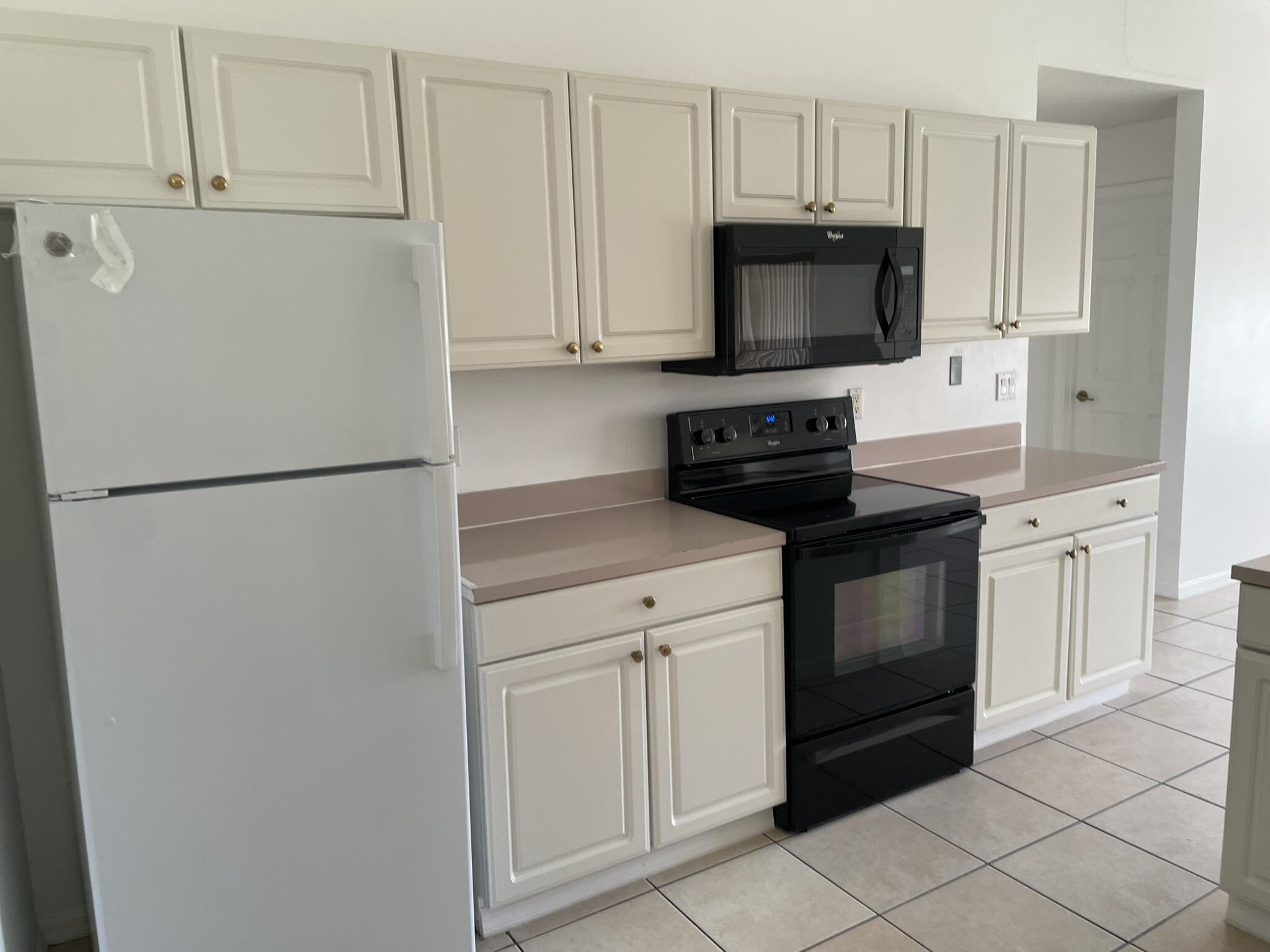 4448 Northwest Bighorn Avenue Port St. Lucie, FL 34983 - Photo 8 of 19 a kitchen with white cabinets and stainless steel appliances