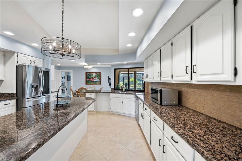 2209 Regal Way Naples, FL 34110 - Photo 9 of 24 a large kitchen with granite countertop a large counter top cabinets appliances and a chandelier