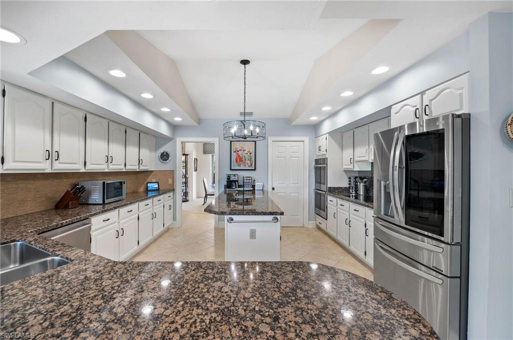 2209 Regal Way Naples, FL 34110 - Photo 10 of 24 a large kitchen with stainless steel appliances kitchen island granite countertop a refrigerator oven a sink dishwasher and white cabinets with wooden floor