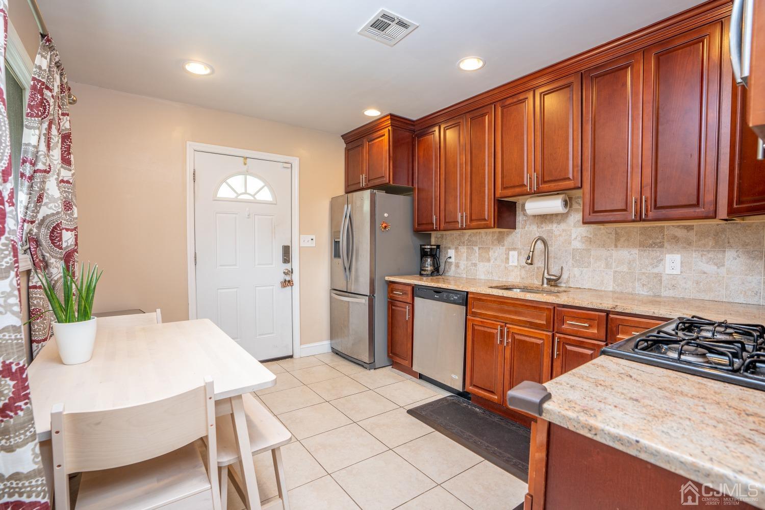 24 Kenmore Road Edison, NJ 08817 - Photo 4 of 21 a kitchen with stainless steel appliances kitchen island granite countertop a refrigerator a sink dishwasher and wooden cabinets