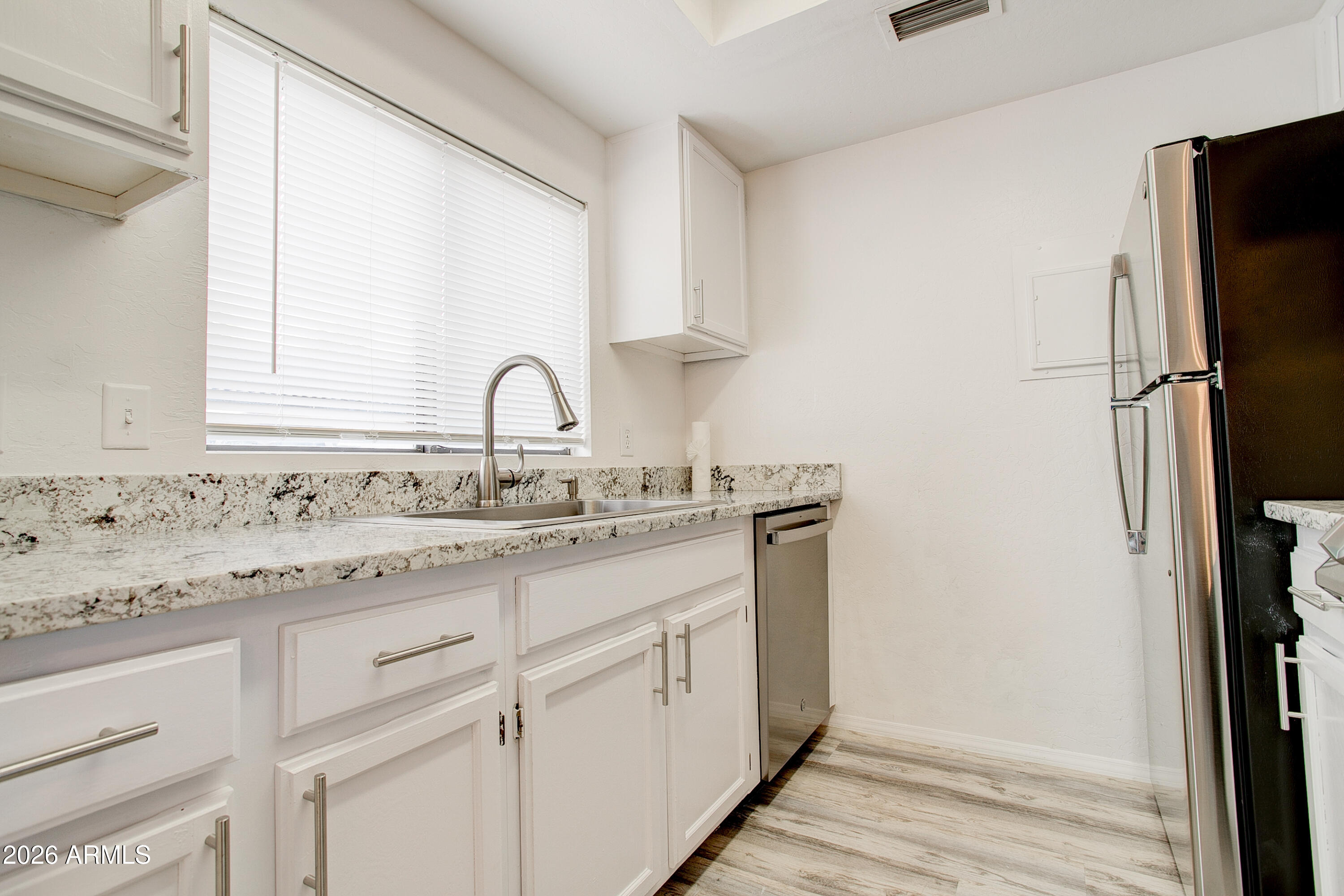 2215 West Augusta Avenue, Unit 102 Phoenix, AZ 85021 - Photo 27 of 39 a sink with granite countertop white cabinets and a refrigerator