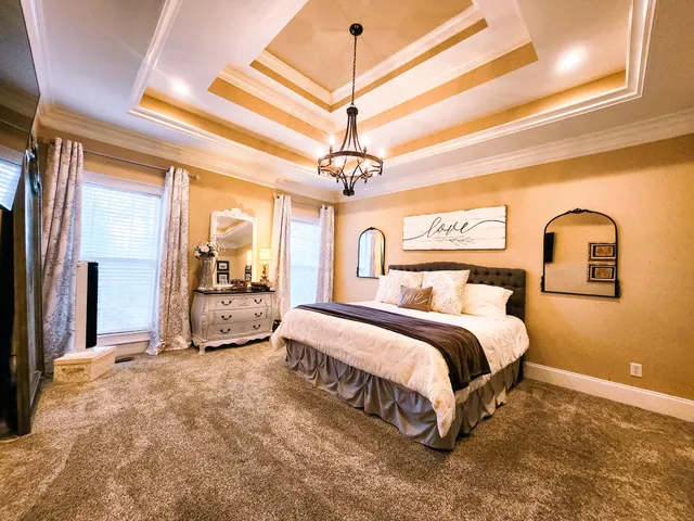 a spacious bedroom with a bed a dresser and a chandelier