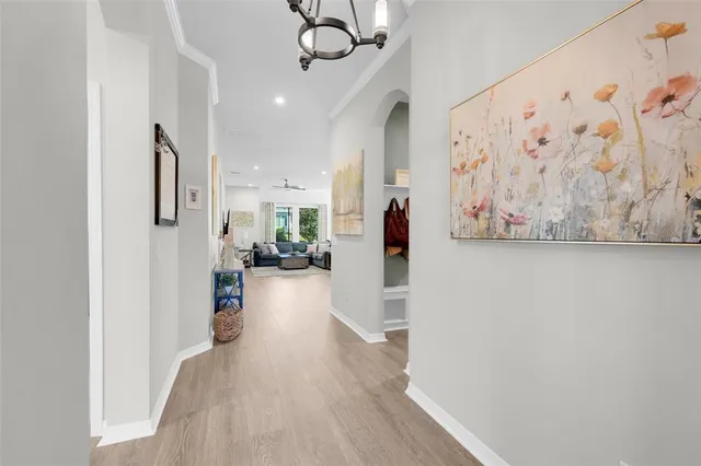 a view of a hallway with wooden floor and a chandelier