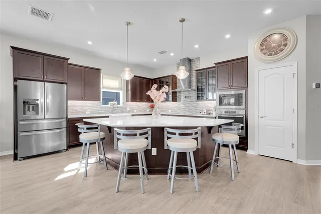 a kitchen with kitchen island granite countertop a dining table chairs cabinets and stainless steel appliances